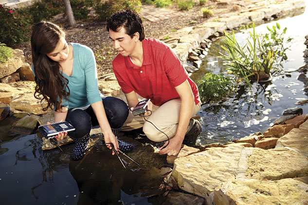 Two students using calculators and data collection sensors at a pond