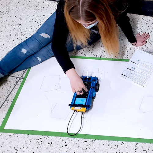 A student programming at TI-Innovator™ Rover using a TI graphing calculator.